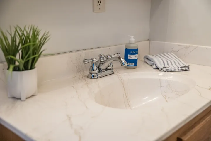 Integrated vanity with a polished chrome faucet and an oval sink, set against a light wall