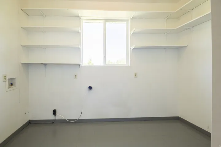 Utility room featuring extensive built-in shelving, a dual-pane window, and grey flooring