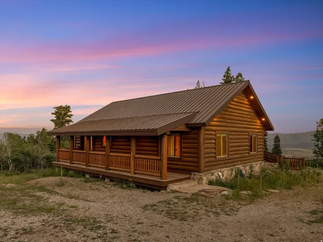 Log cabin exterior featuring a covered porch, wood railing, and metal roofing