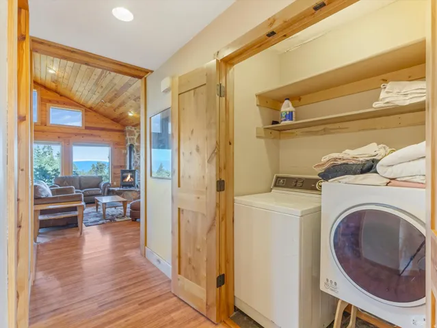 Dedicated laundry closet featuring a stacked washer and dryer, integrated shelving, and a natural wood door