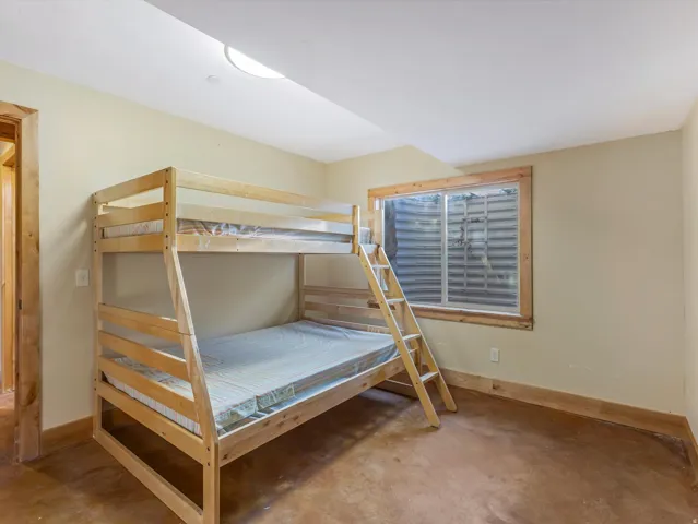 Wood-frame bunk beds with a ladder, set on a dark, textured floor