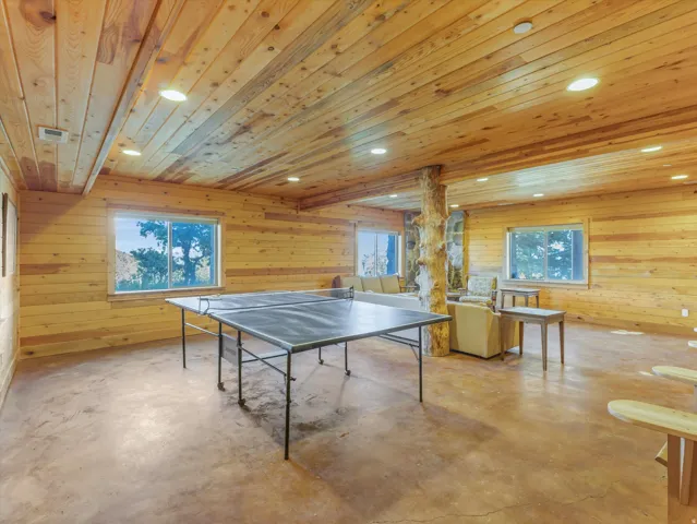 Spacious recreation room featuring natural wood-paneled walls and ceiling with recessed lighting