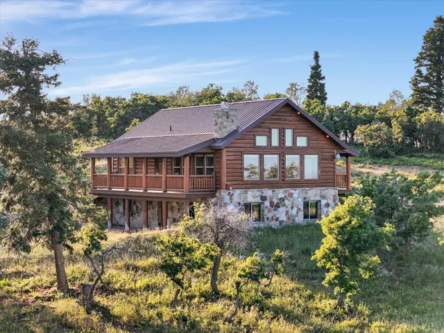 Log home featuring a metal roof, stone foundation, and a full-width balcony with wood railings