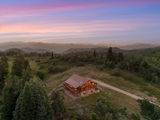 Custom log home featuring a stone foundation, wood siding, and an expansive deck