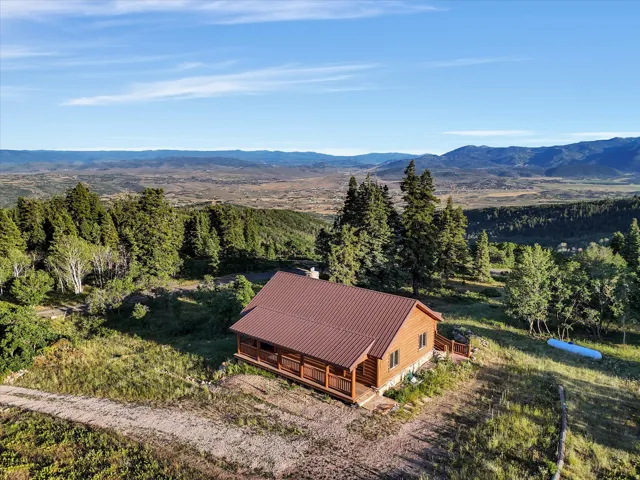 Log cabin residence featuring a durable metal roof, natural wood siding, and a surrounding elevated deck