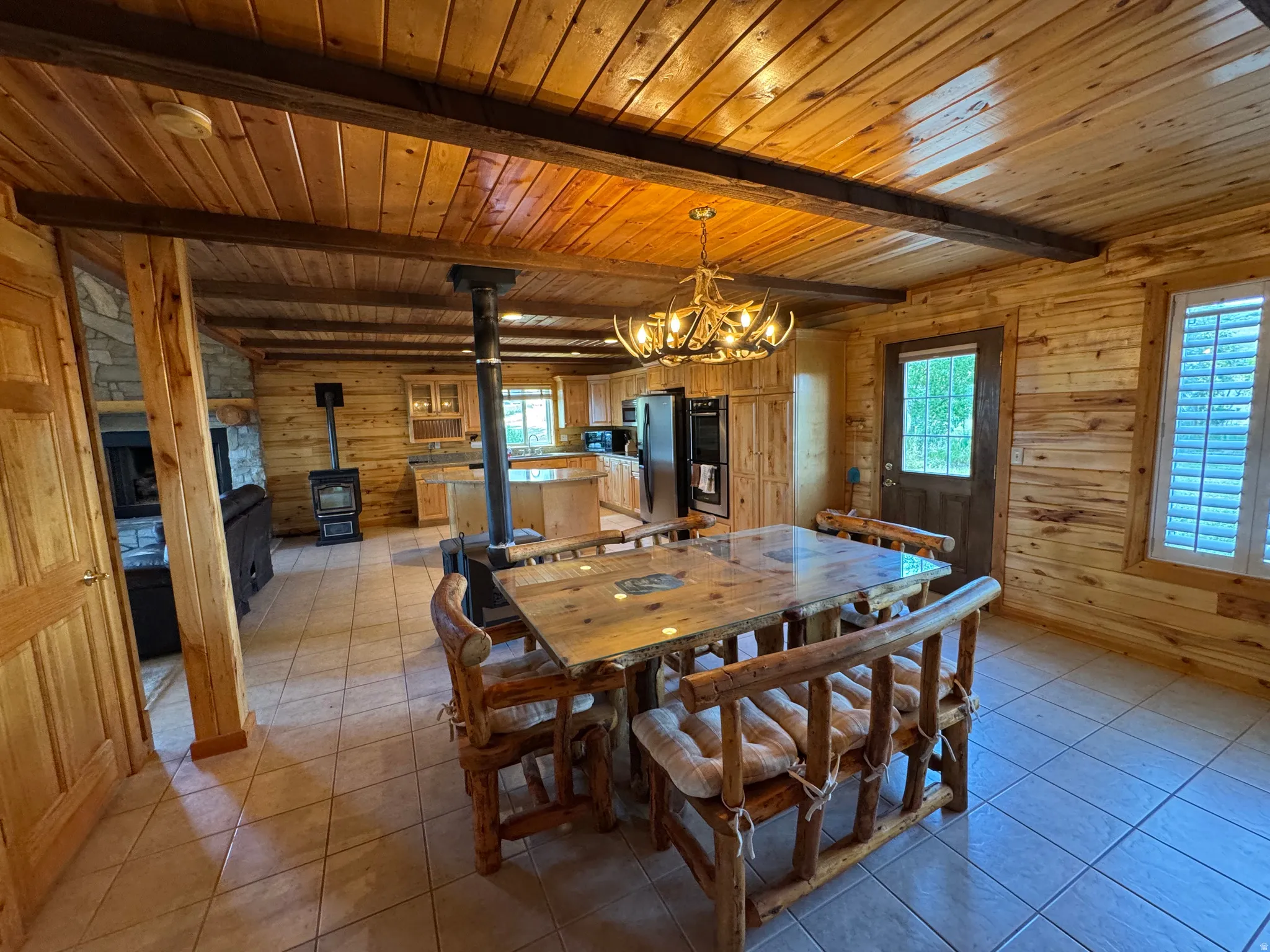 Spacious room featuring wood plank walls, wood plank ceiling with exposed beams, and light-toned tile flooring