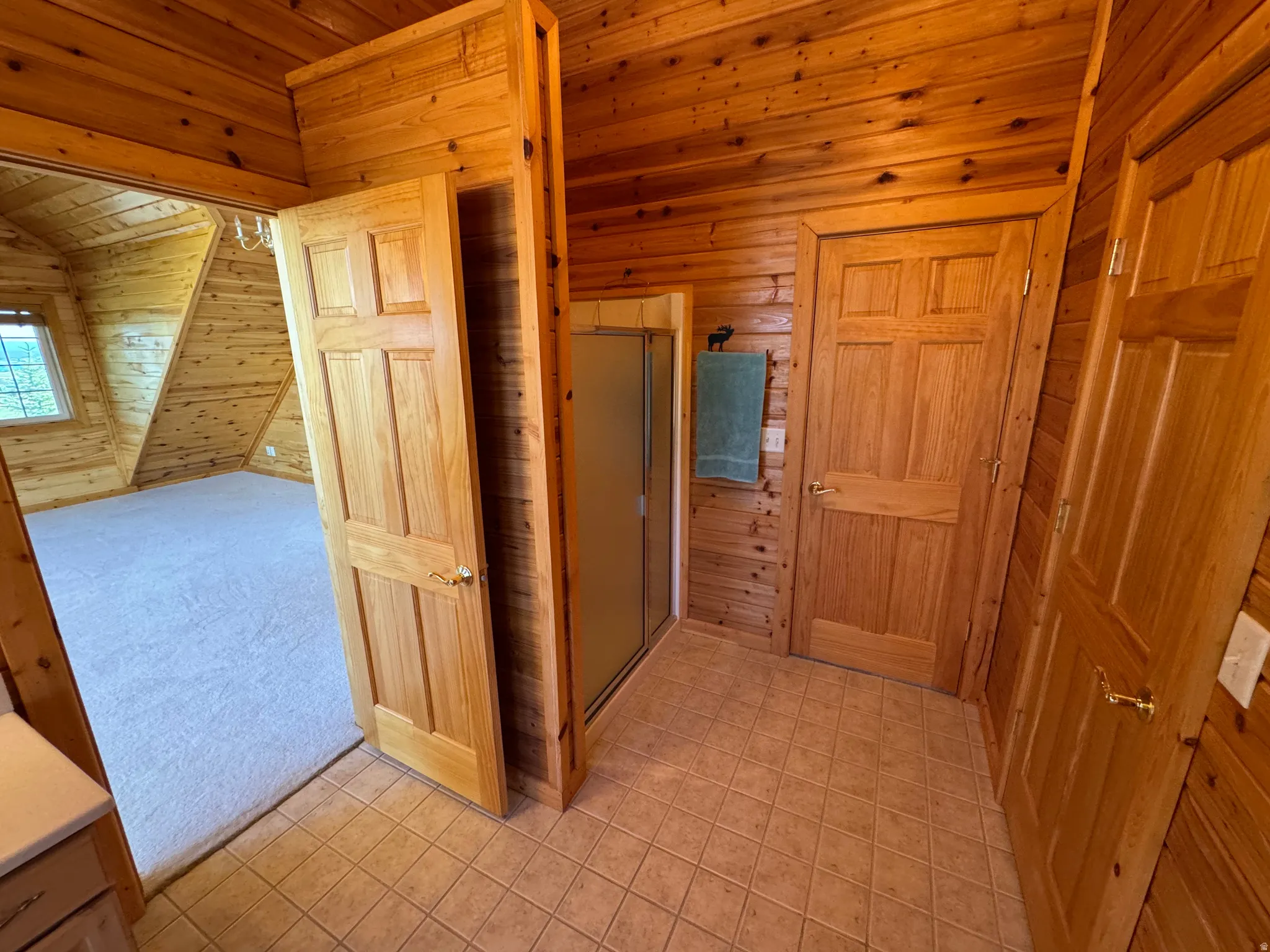 Wood-paneled interior featuring a shower enclosure with frosted glass, solid wood doors, and tiled flooring