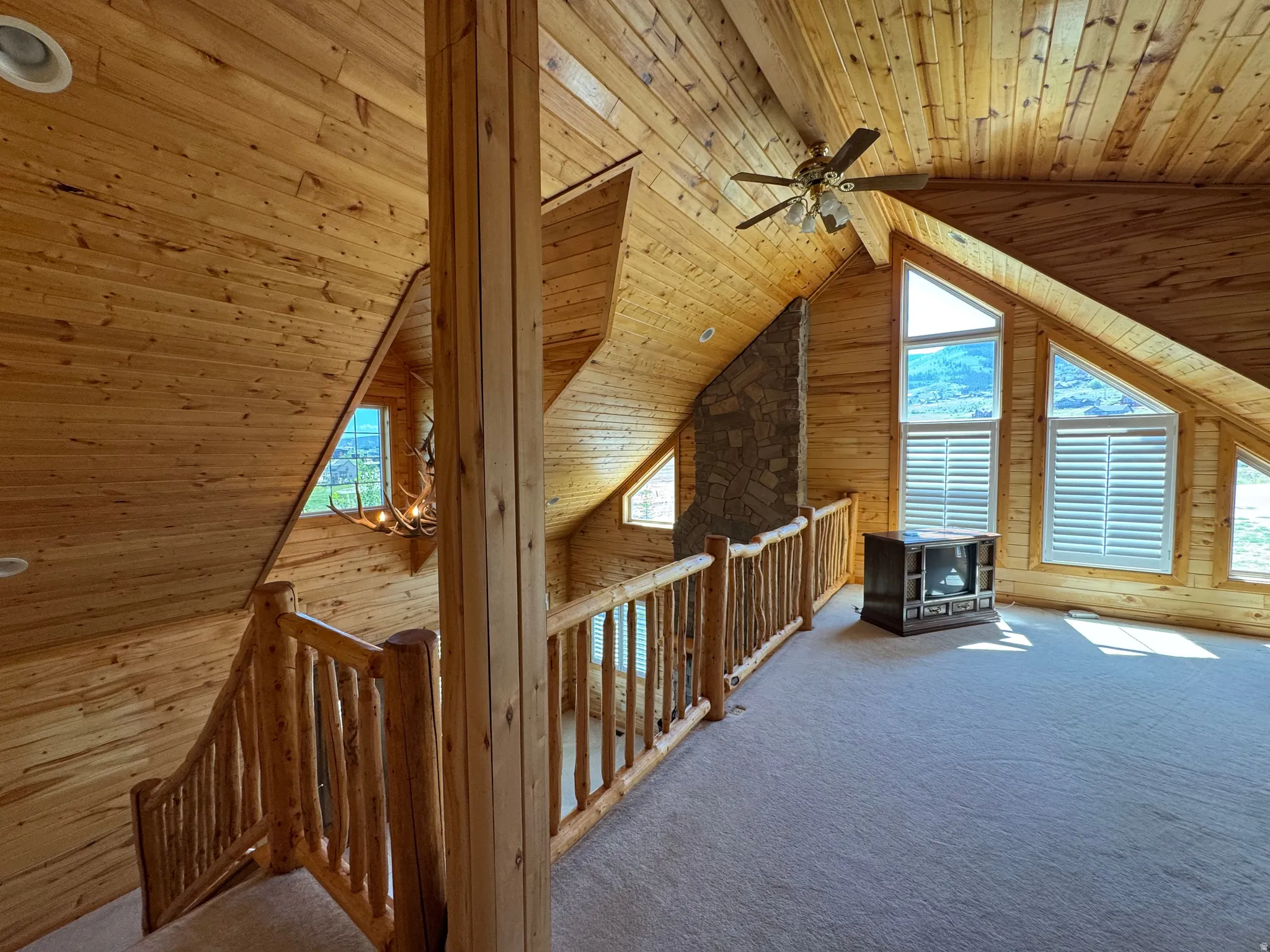 Upper-level open space with wood-paneled walls and ceilings, recessed lighting, and a ceiling fan