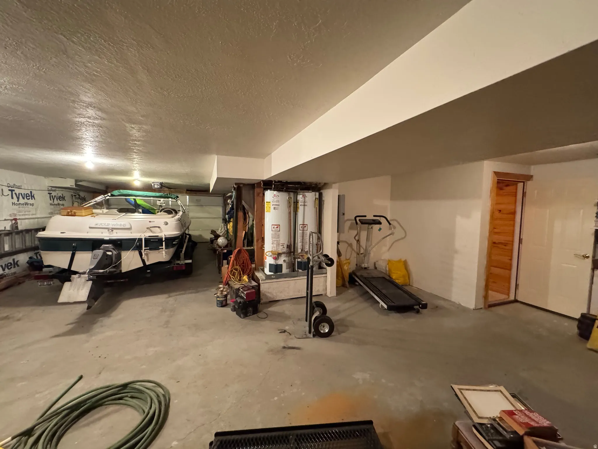 Expansive garage space featuring a concrete floor, painted white walls, and a textured ceiling with recessed lighting