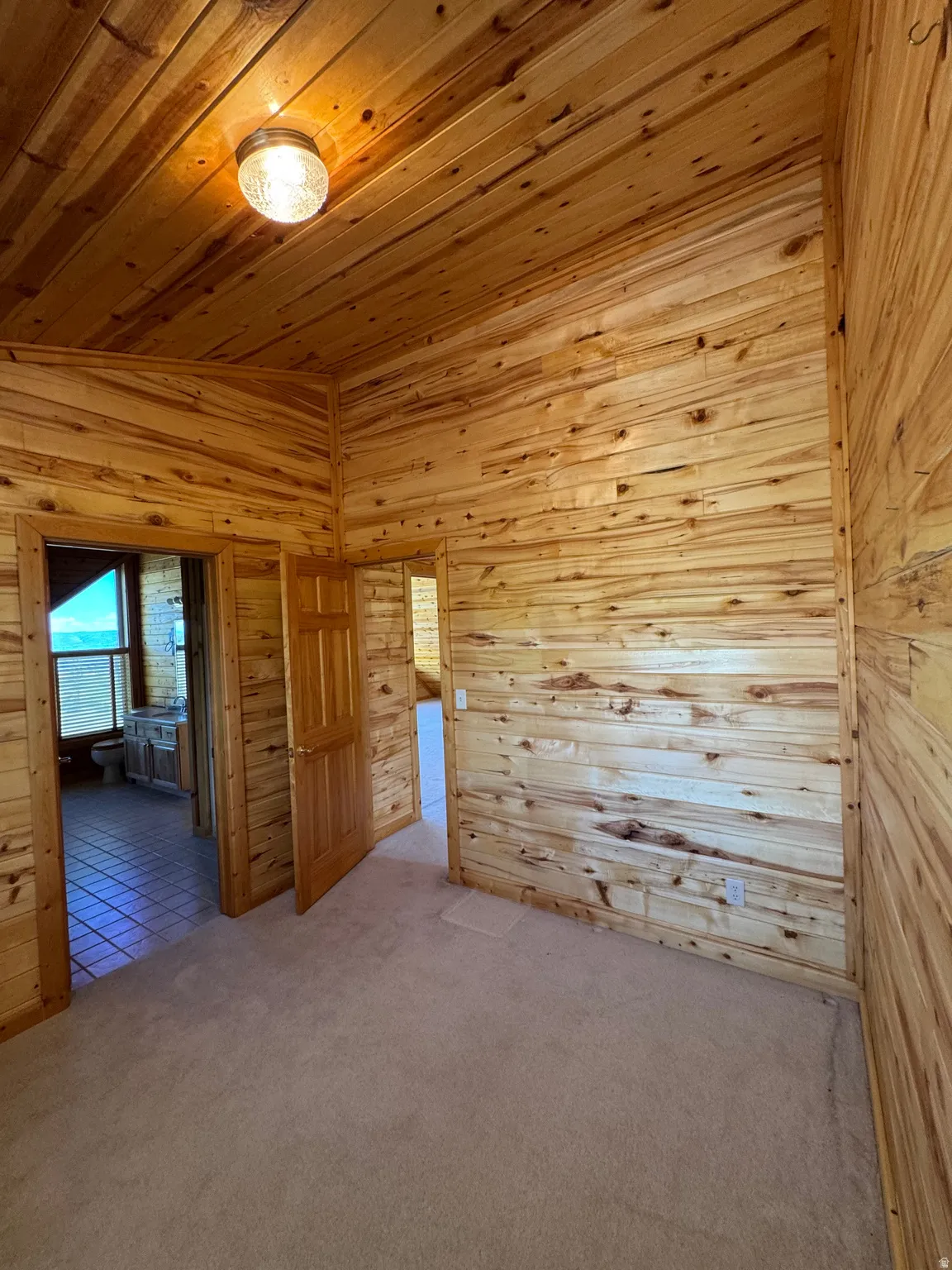 Room featuring natural wood plank walls and ceiling, wall-to-wall carpeting, and a flush-mount ceiling light fixture