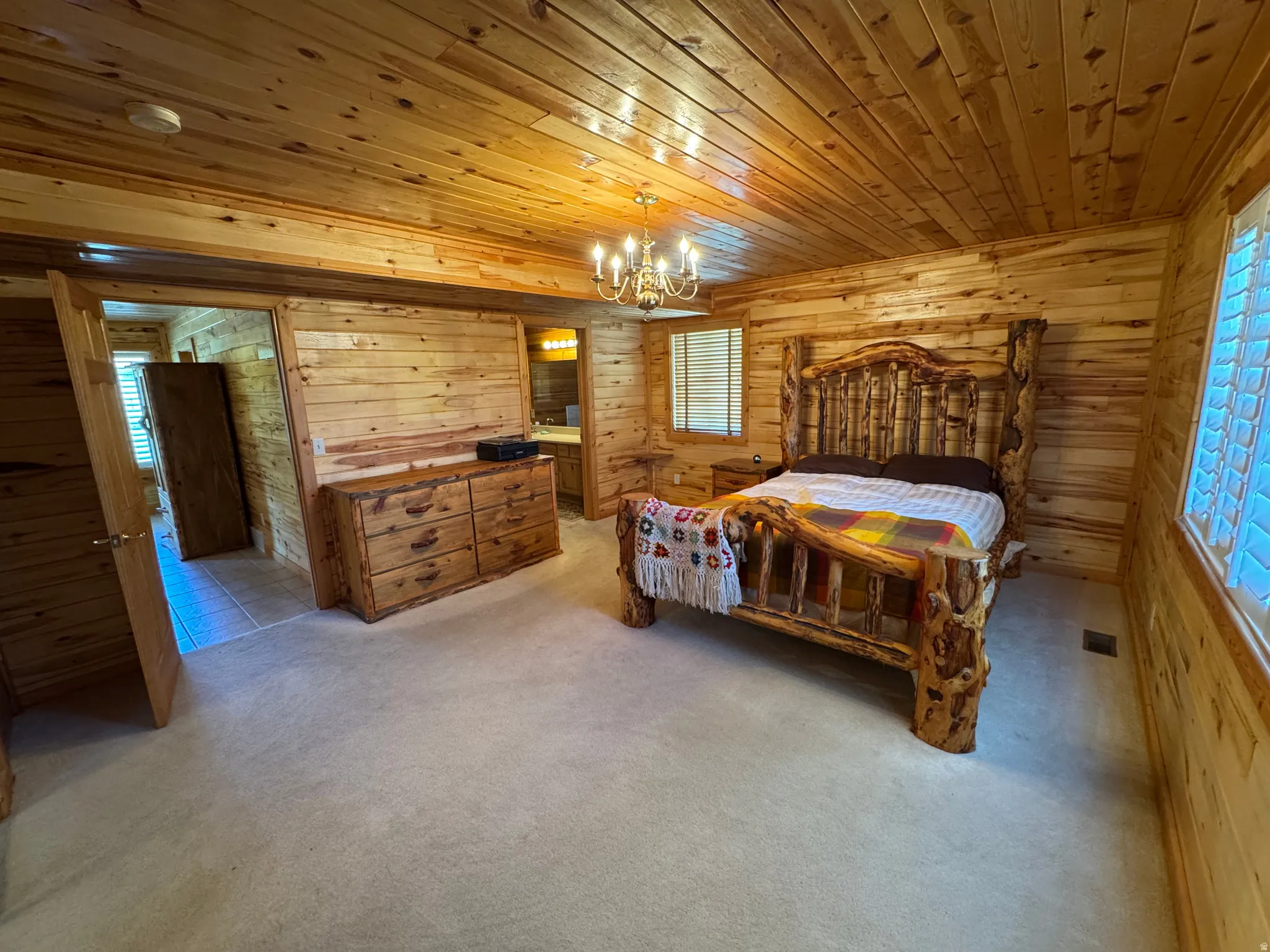 Wood-paneled room featuring a wood-finish ceiling, light-toned carpeting, and multiple windows with plantation shutters