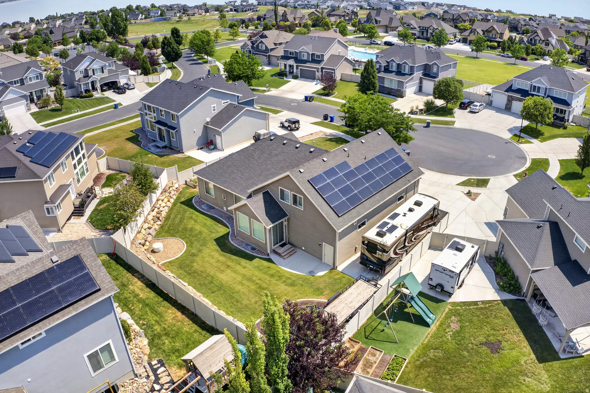 Two-story residence featuring a neutral-toned exterior, dark shingle roof, and multiple solar panel arrays