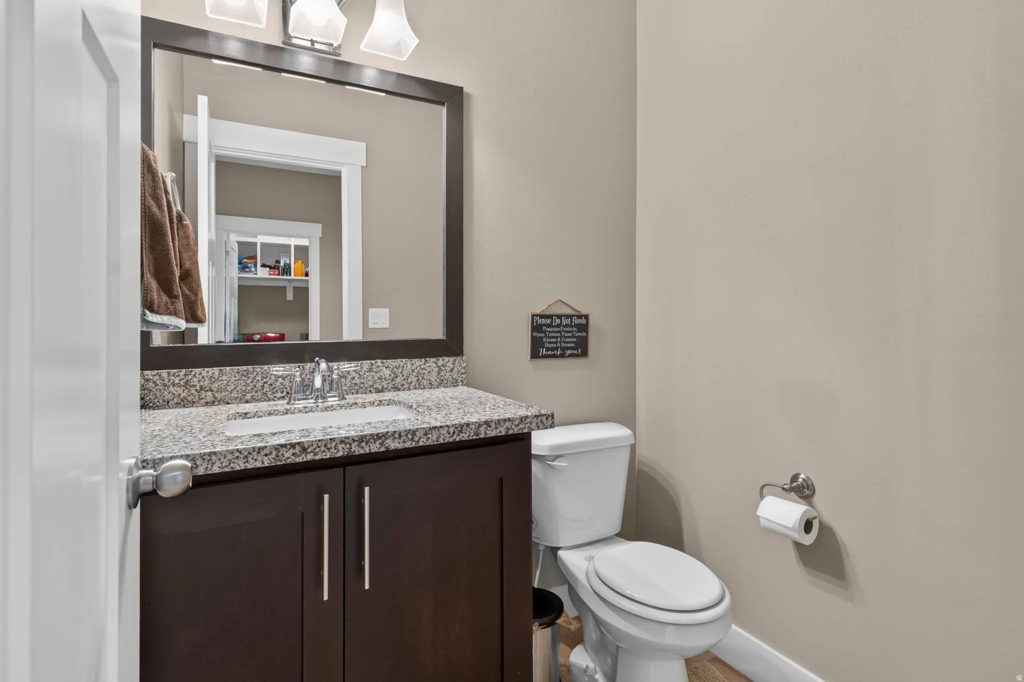 Bathroom vanity featuring a granite countertop, undermount sink, and dark wood cabinetry with brushed nickel hardware