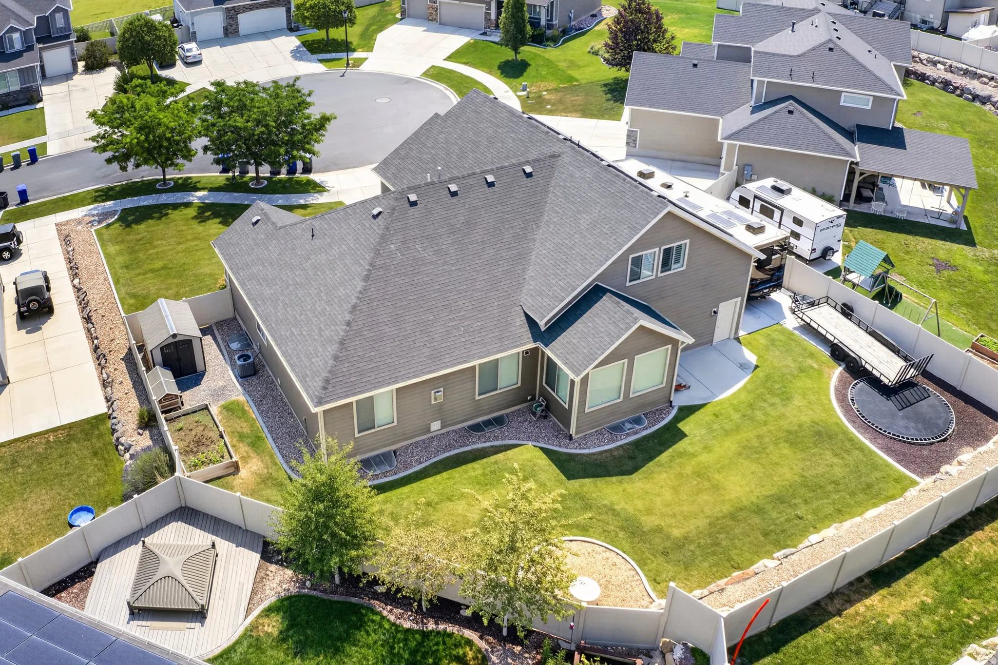 Spacious residential property featuring a large backyard with manicured lawn, an in-ground trampoline, and a dedicated gravel area