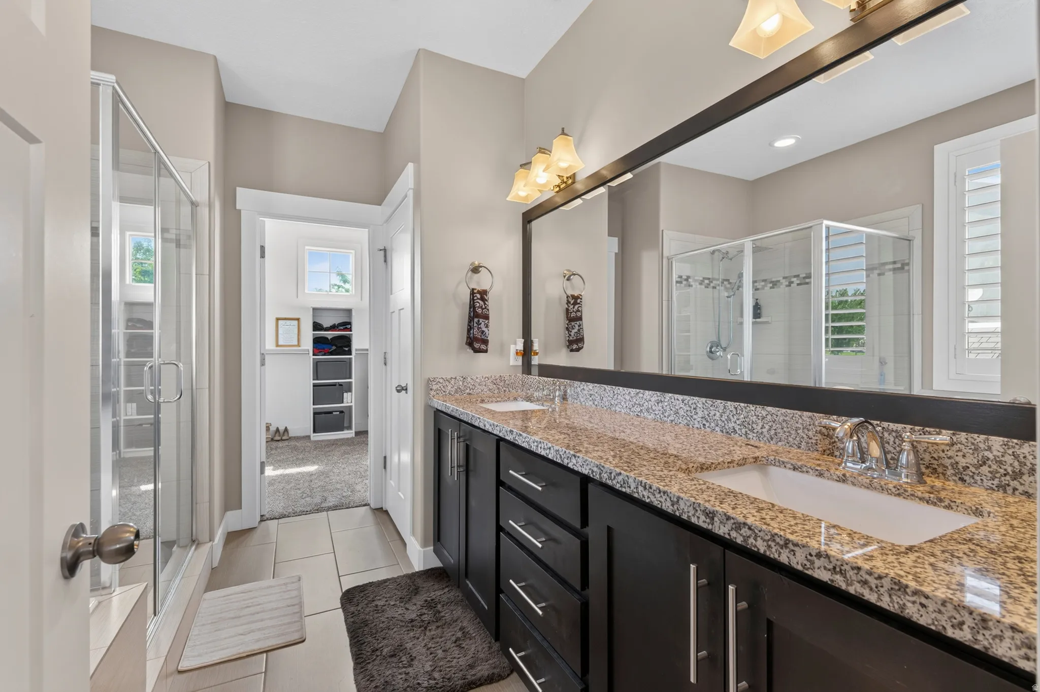 Bathroom vanity featuring a speckled countertop, dual undermount sinks, and dark wood cabinetry