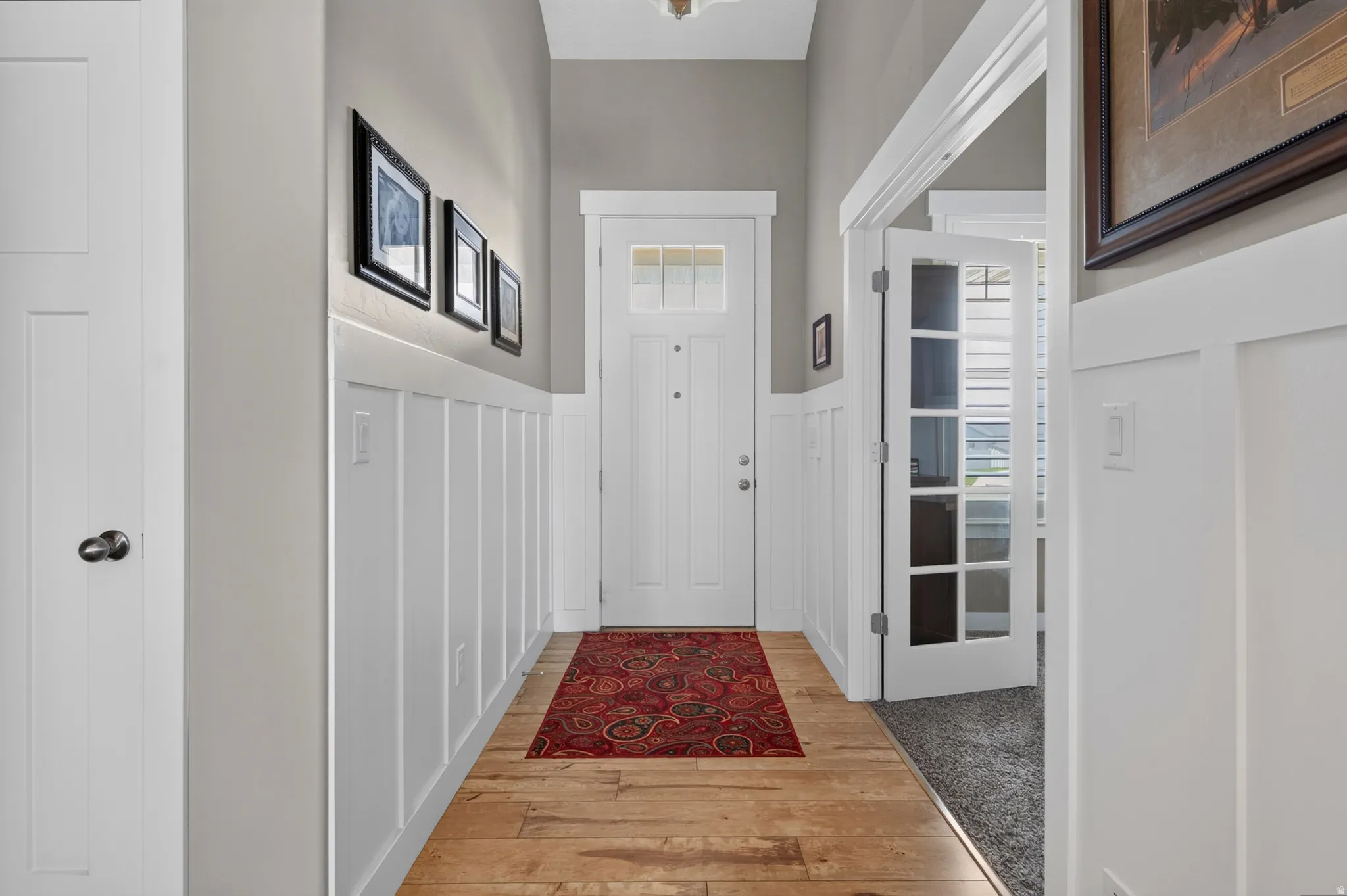 Entryway featuring wood-finish flooring, white board and batten paneling, and a door with an integrated window
