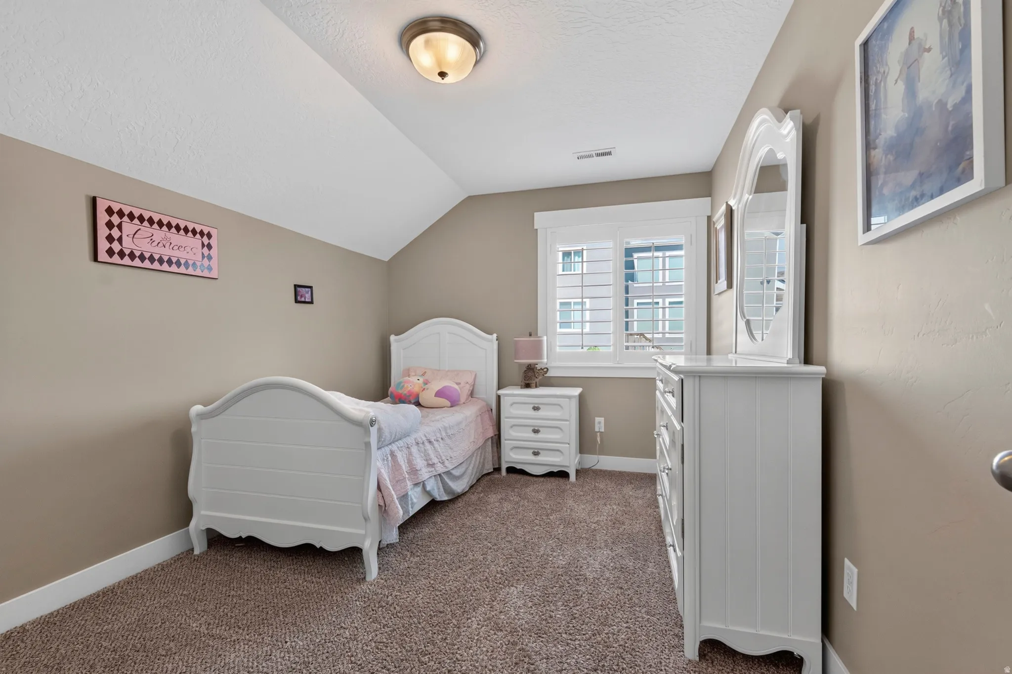 Room featuring textured taupe walls and sloped ceilings with a flush mount light fixture