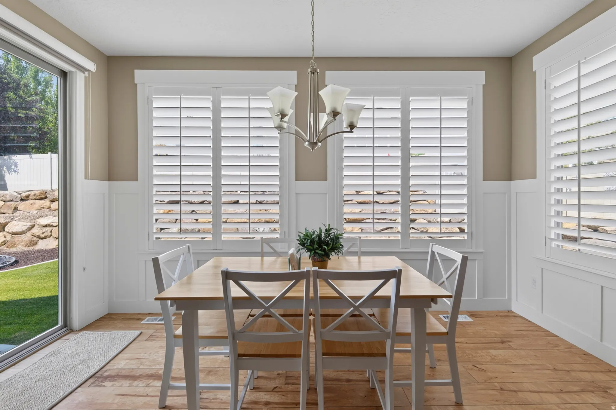 Dining area featuring wood-finish flooring, wainscoting, and a multi-light chandelier