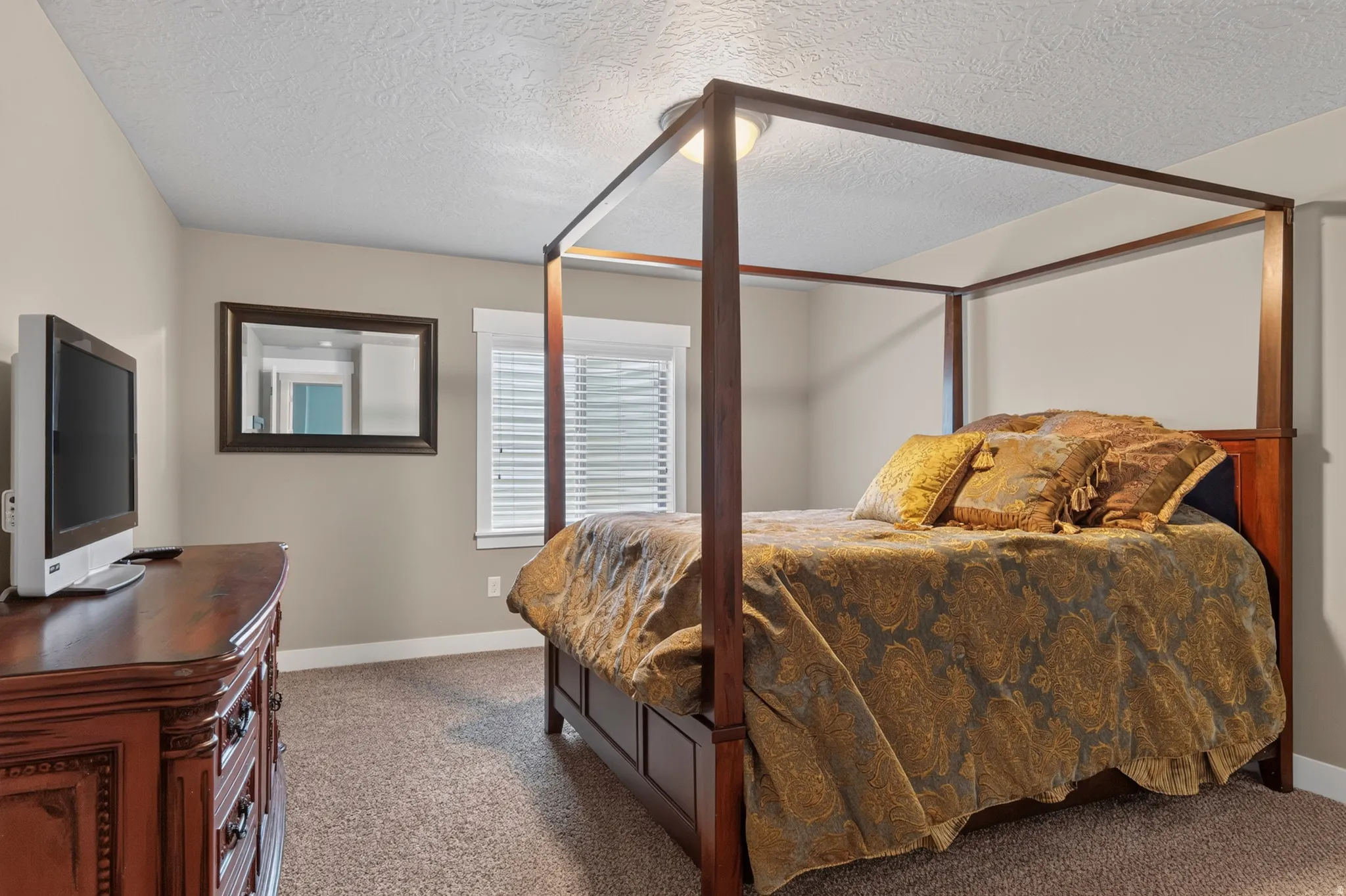 Carpeted bedroom featuring a large window with blinds, neutral wall paint, and white trim