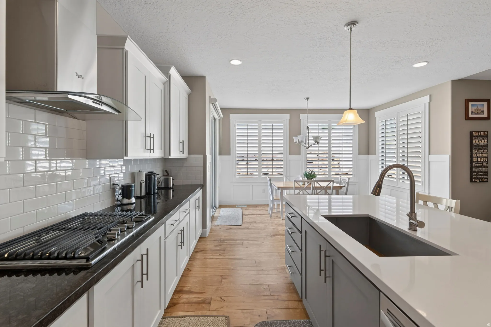 Kitchen featuring white shaker-style cabinetry, black countertops, a stainless steel gas cooktop, and a subway tile backsplash