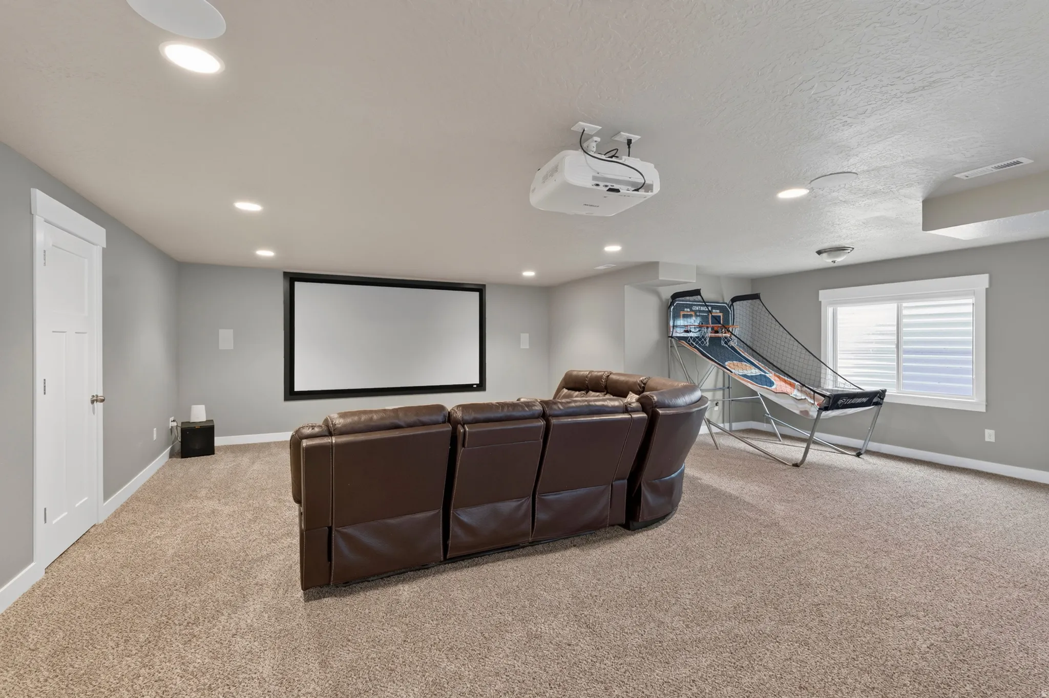 Dedicated media room featuring a large projection screen, mounted projector, and recessed lighting