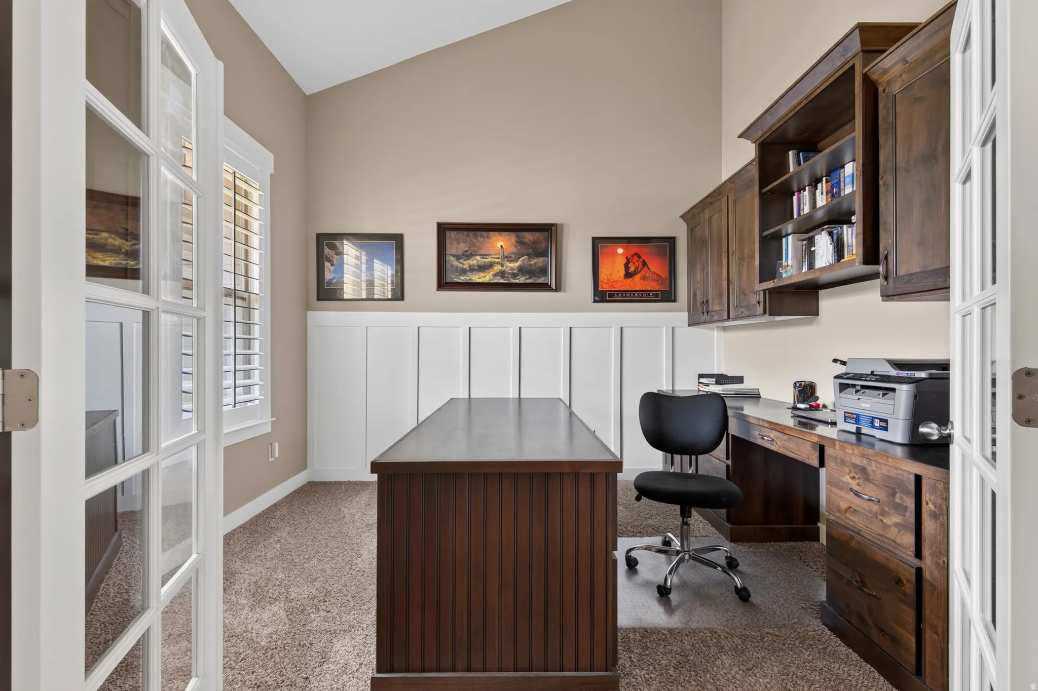 French doors open into a functional room featuring built-in cabinetry, a built-in wood desk, and high ceilings