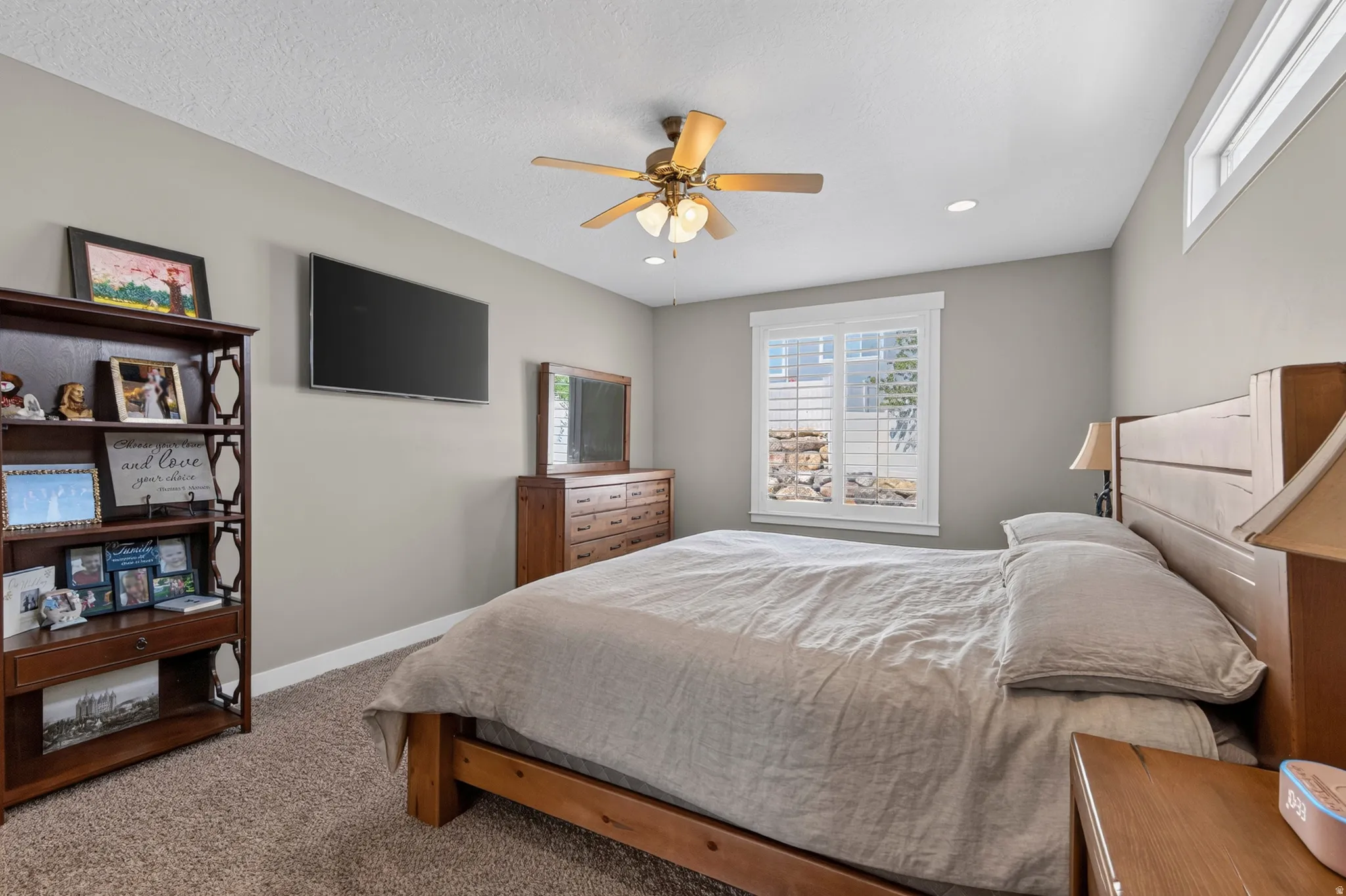 Carpeted room featuring a ceiling fan with light fixture, recessed lighting, and a white-trimmed window with blinds