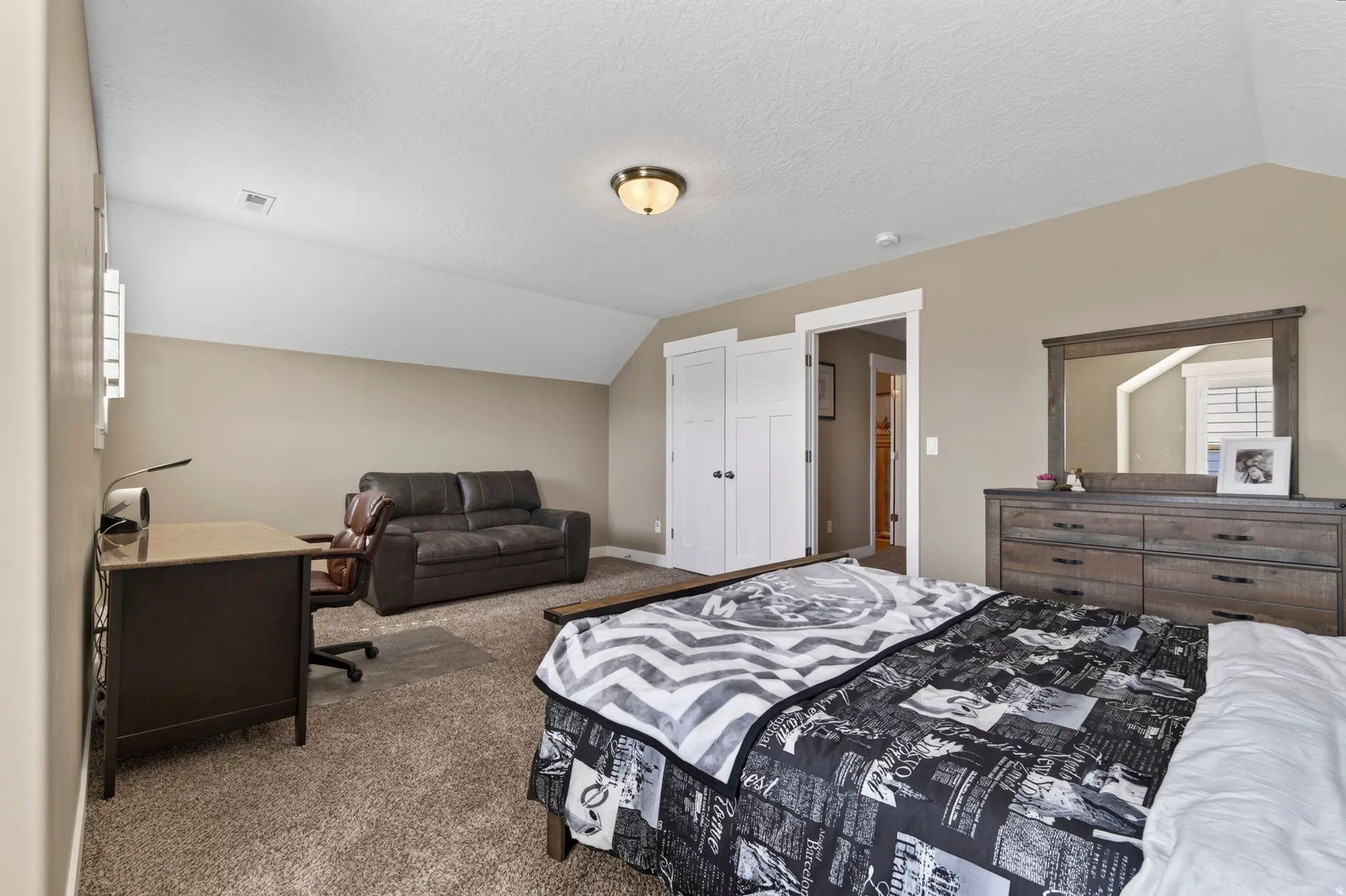Spacious room featuring vaulted ceilings, neutral wall tones, and plush carpet flooring