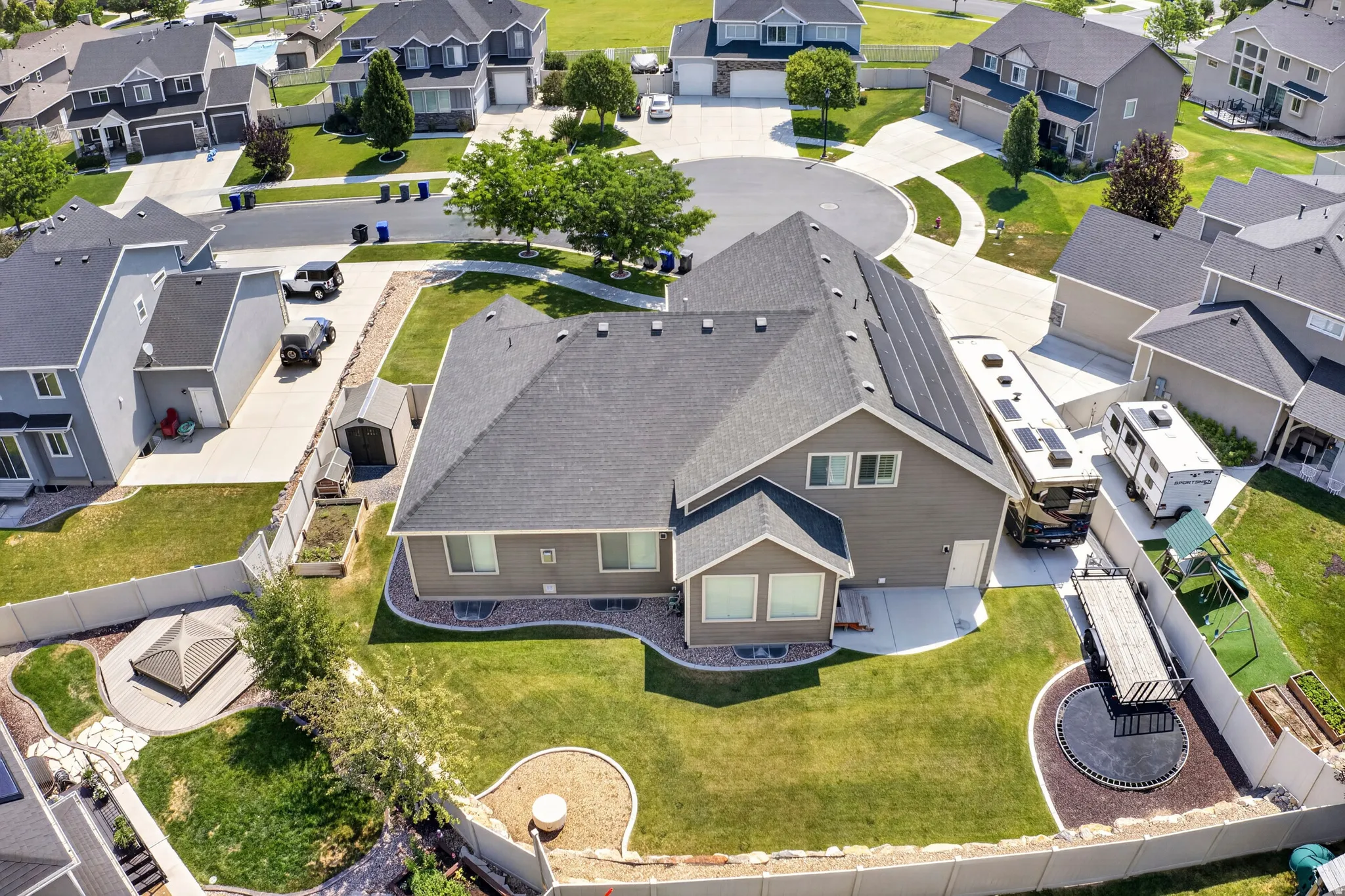 Aerial view of a residential property featuring a gray-toned exterior and a dark roof with multiple solar panels