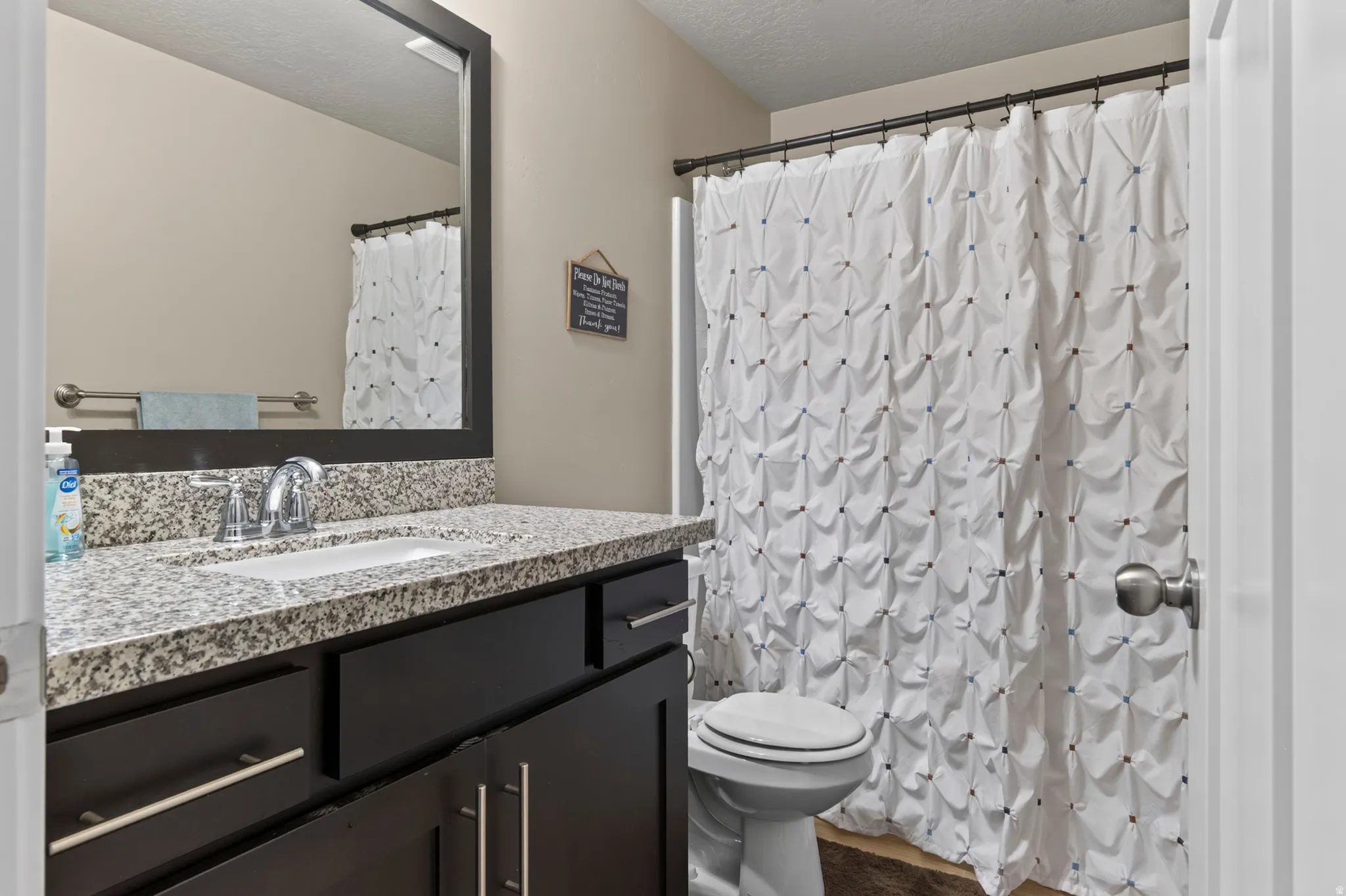 Bathroom featuring a dark wood-finish vanity with an integrated sink, polished chrome faucet, and stone-finish countertop