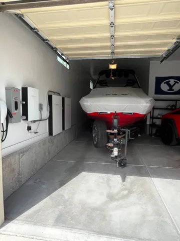 Extended-depth garage featuring concrete flooring and a built-in Tesla Powerwall system