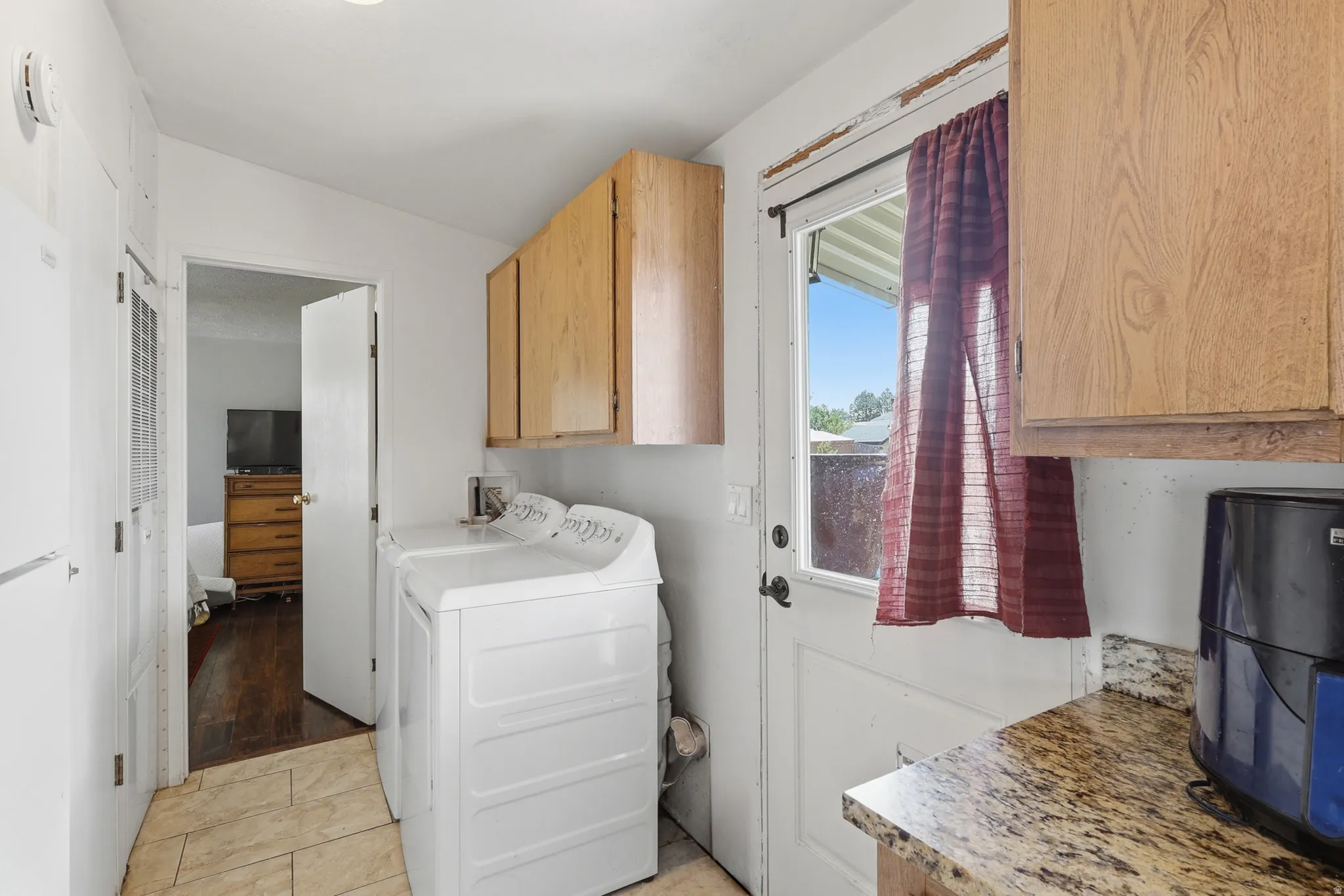 Laundry area featuring tile flooring, wood cabinetry, a granite-finish countertop, and an exterior door with a window