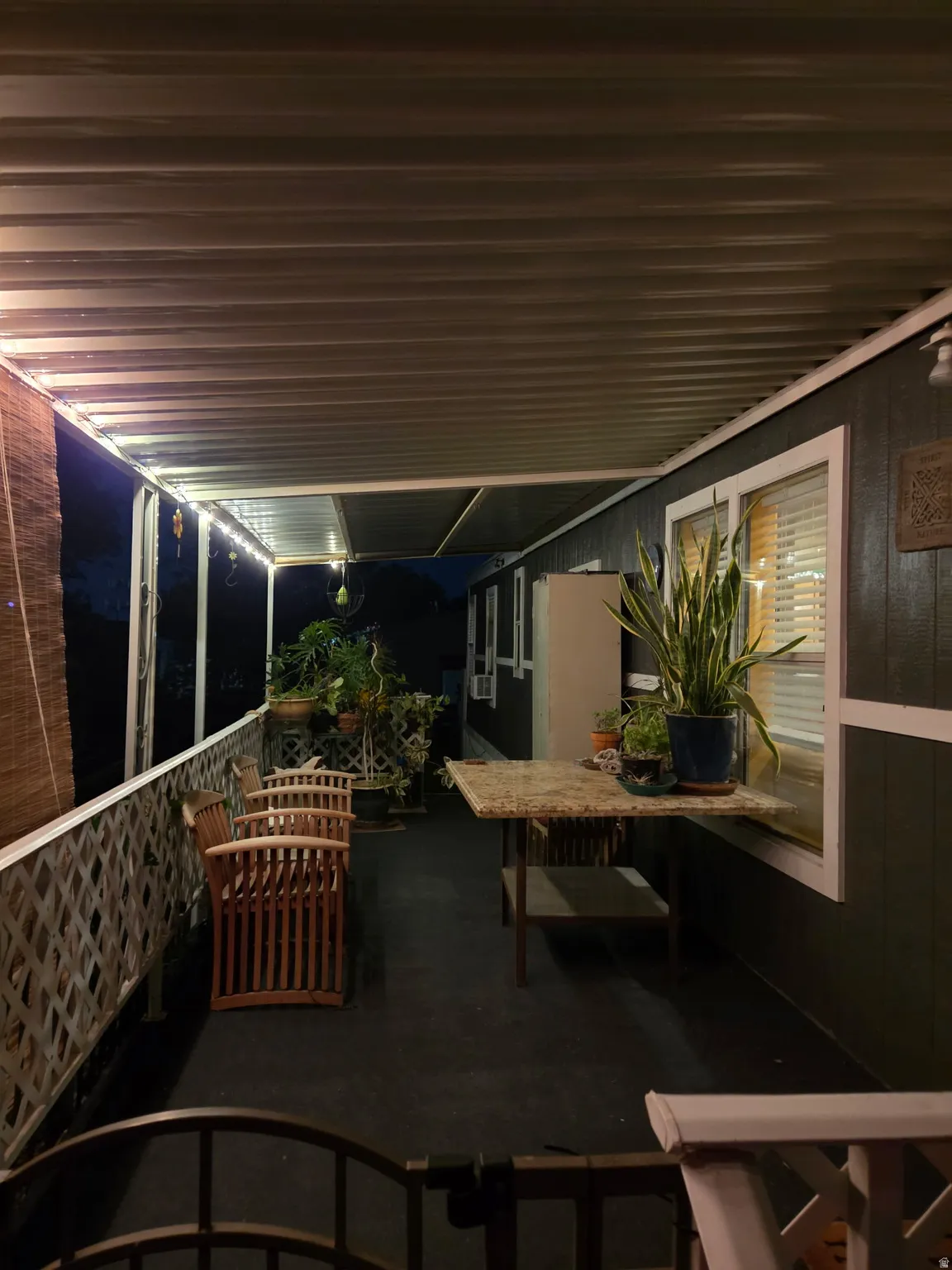 Expansive covered patio featuring a dark-toned floor, white lattice railing, and a white corrugated ceiling