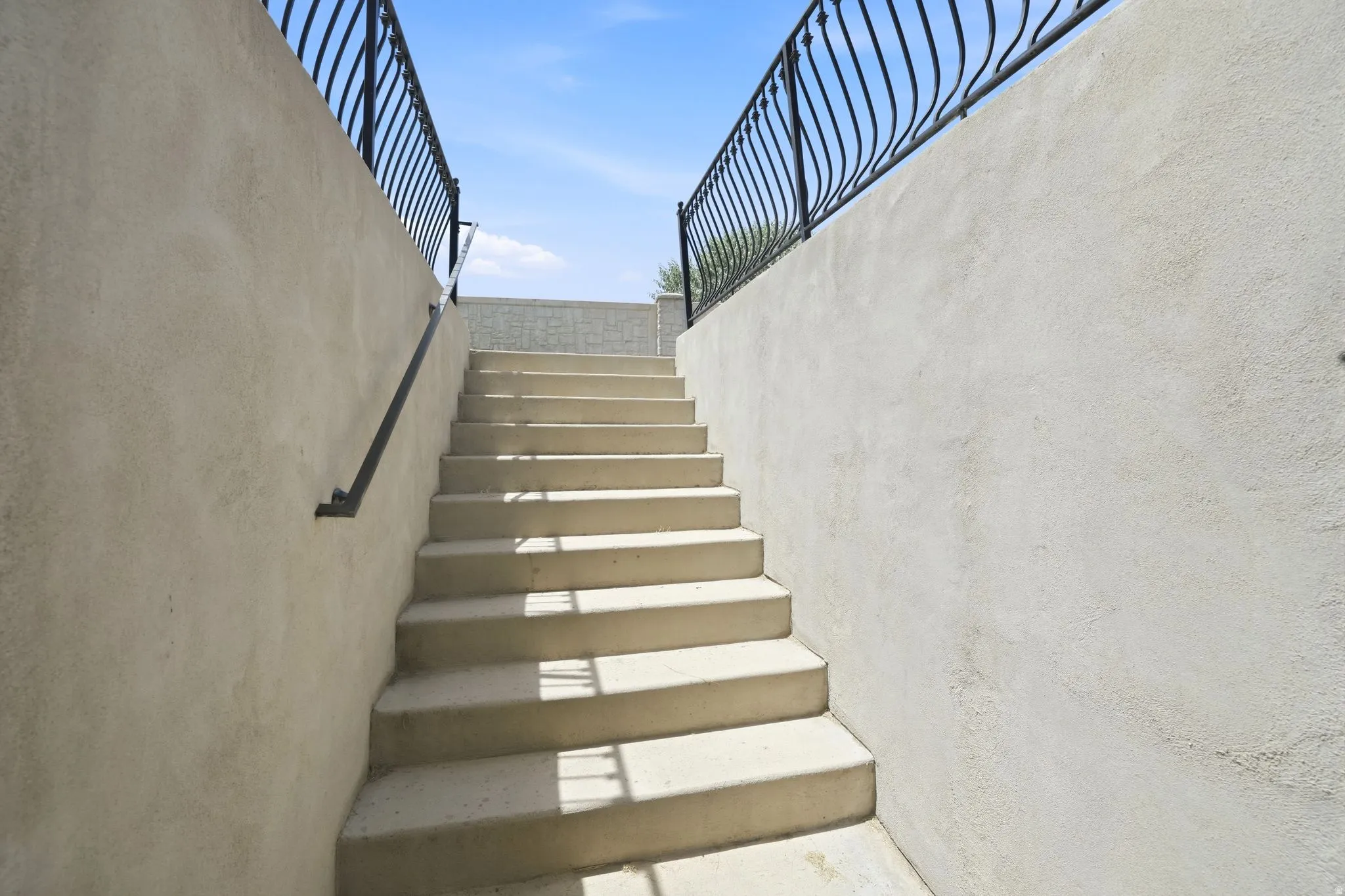 Concrete exterior staircase featuring stucco walls and wrought iron railings