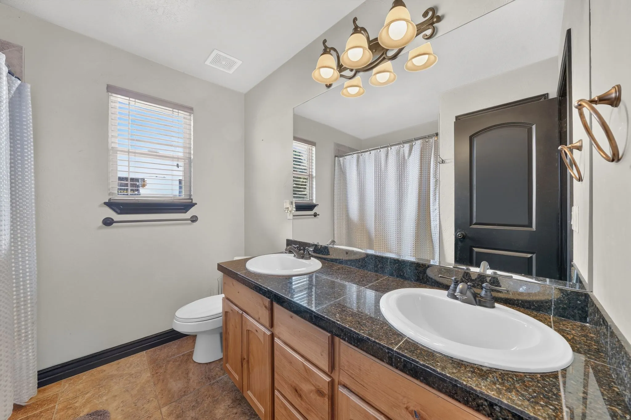 Second Bathroom featuring a dual vanity with wood cabinetry, dark stone countertops, and undermount sinks