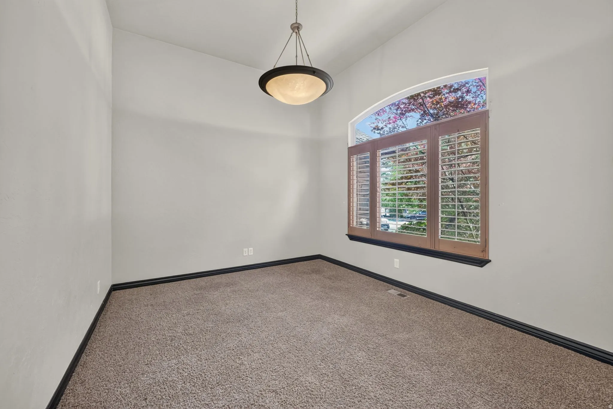 Interior room featuring a vaulted ceiling textured light-toned walls with plantation shutters