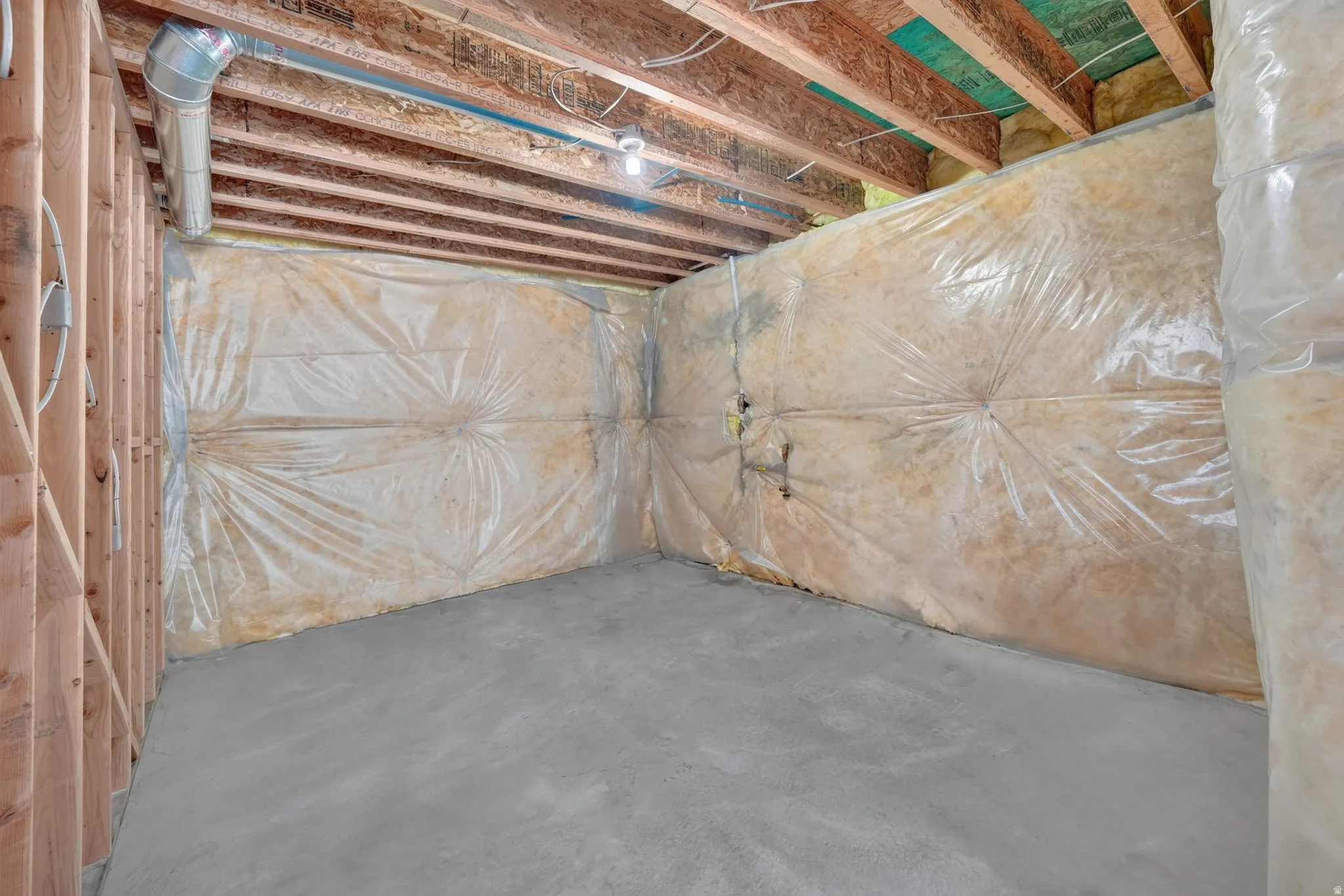 Unfinished basement with concrete flooring, exposed wood framing, and ceiling joists