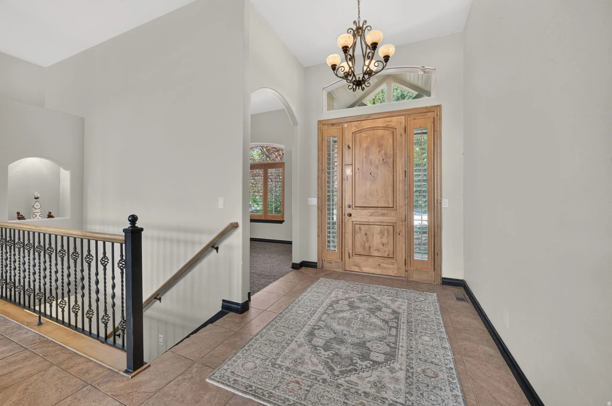 Foyer featuring a natural wood front entry door with sidelights, a transom window, and a chandelier
