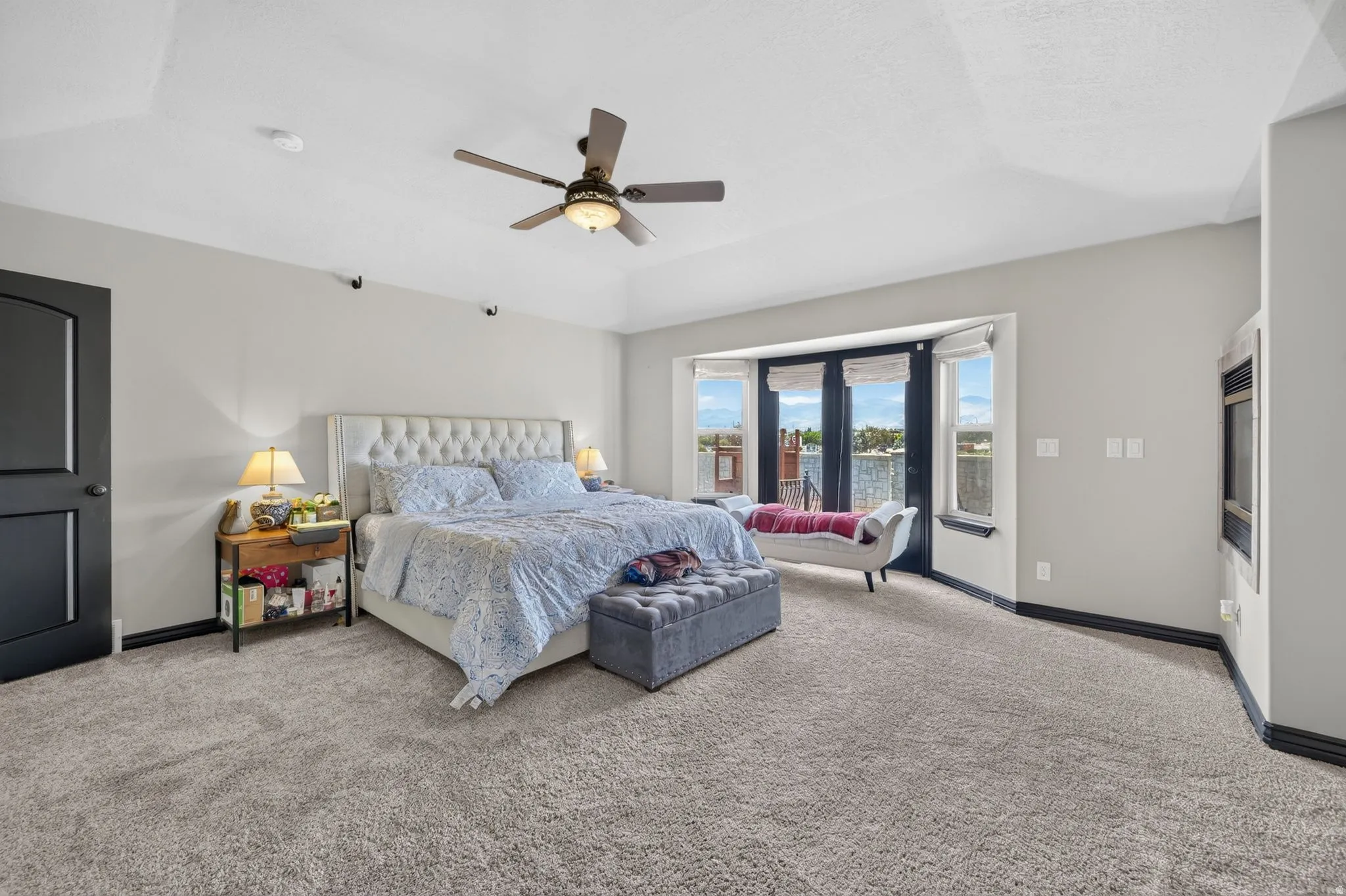 Spacious Primary room featuring light-colored carpeting, a multi-pane bay window, and a ceiling fan with integrated lighting