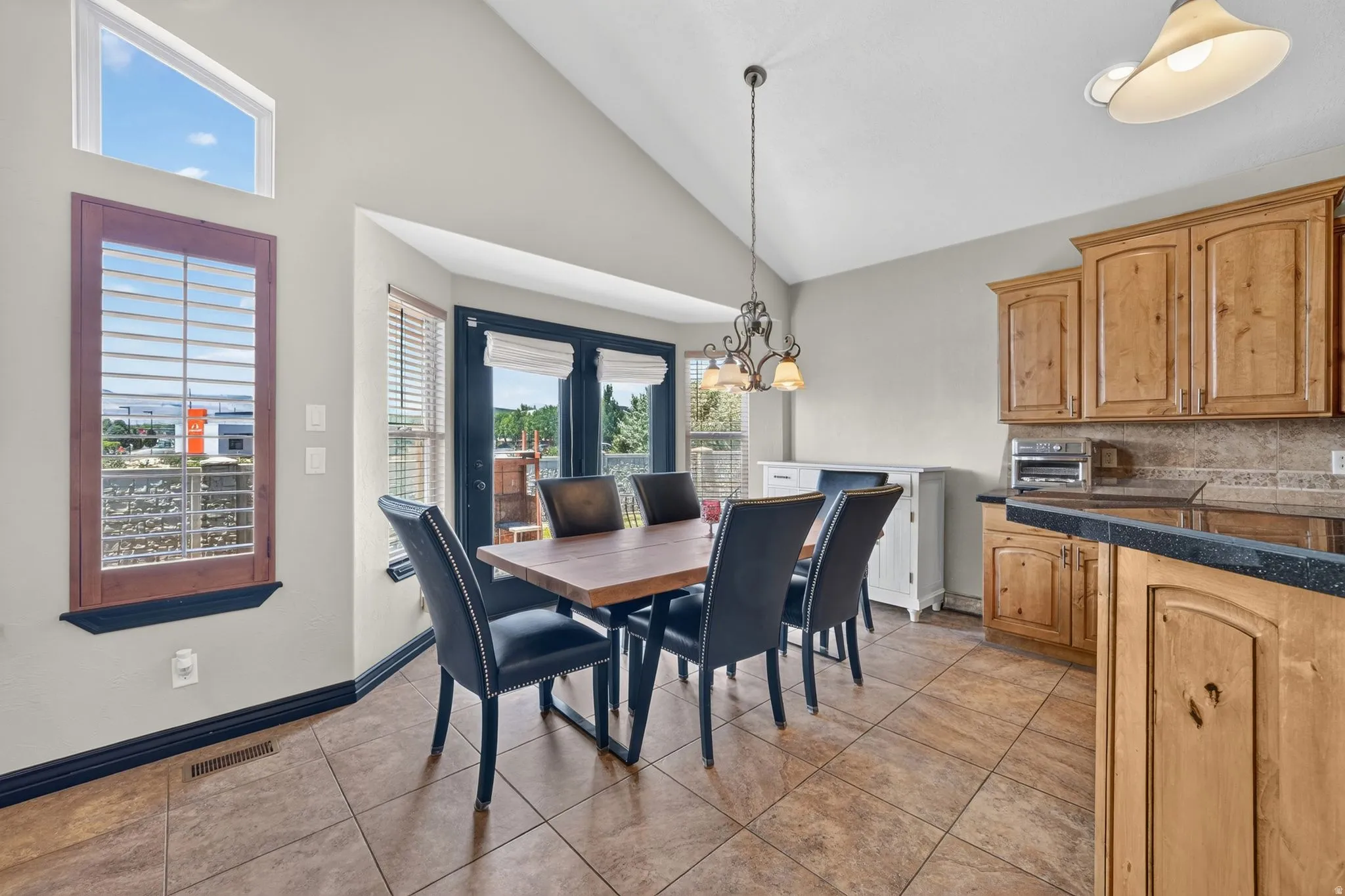 Dining area featuring vaulted ceilings with a transom window, tile flooring, and a bay window with exterior access