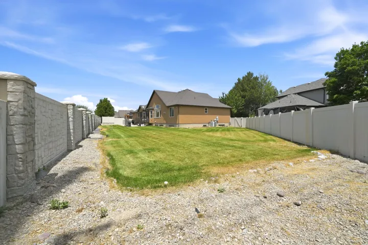 Spacious outdoor area featuring a manicured lawn, stone-finish privacy fencing, and a vinyl privacy fence