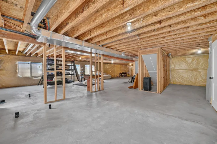 Unfinished basement featuring exposed wood joists, concrete flooring, framed interior walls, and visible ductwork