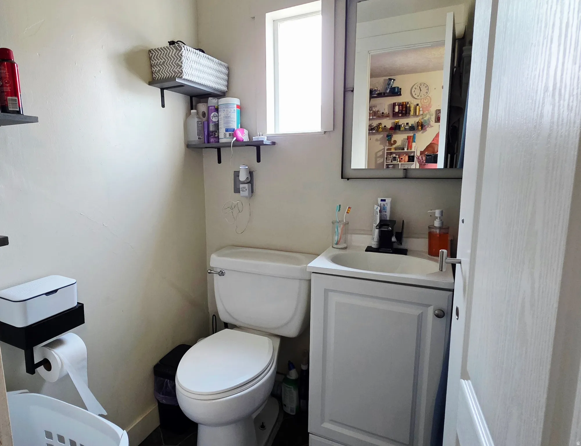Compact bathroom featuring a white vanity with integrated sink, a wall-mounted medicine cabinet, and a white toilet