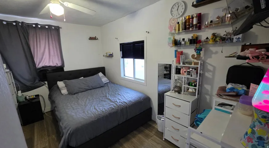 Room featuring wood-finish flooring, white walls, and a window with blinds