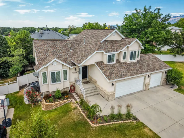 Exterior featuring a pitched roof, light-toned stucco siding, and stone accents