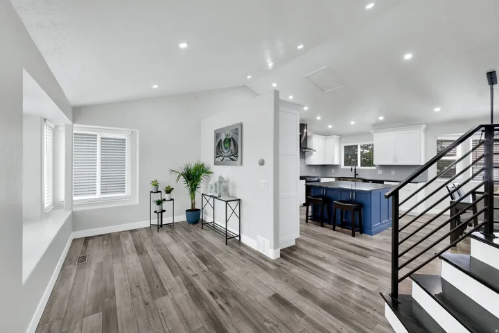 Open-concept living space featuring upgraded NuCore performance ridged-core LVP flooring, recessed lighting, and a prominent kitchen with a blue island