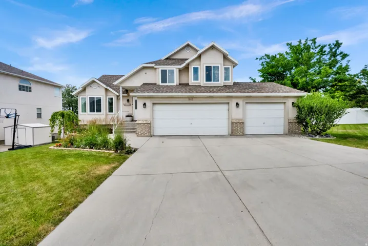 Contemporary stucco exterior featuring a multi-car driveway, attached 3-car garage, and a manicured lawn