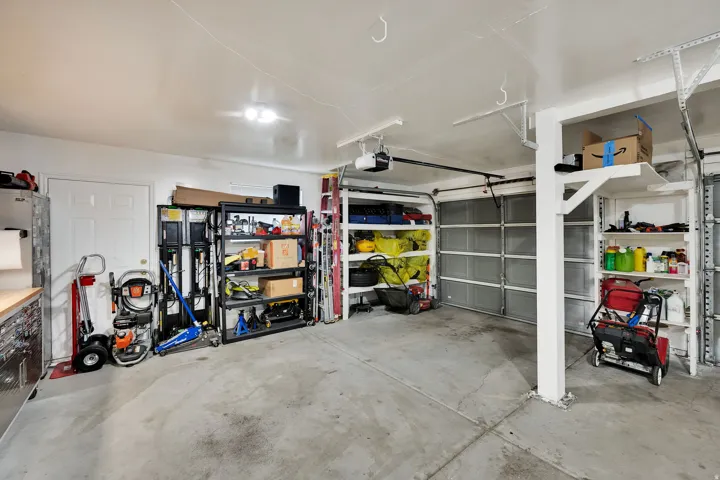 Spacious garage with exposed concrete flooring, overhead lighting, and white panel doors