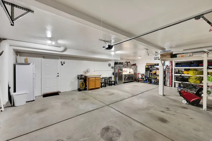 Spacious garage featuring concrete flooring, overhead lighting, an interior access door, and built-in shelving units, extra power for all your tools