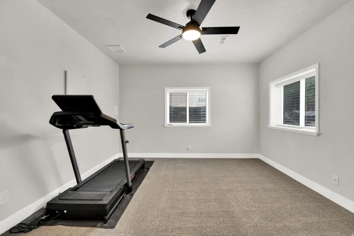 Carpeted room with light gray walls, two windows, and a black ceiling fan with integrated lighting,  9' ceilings, extra thick pad